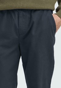 Navy pants featuring an elastic waistband and side pockets, made from a smooth, lightweight fabric with subtle texture and tailored fit.