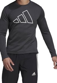 Langärmliges, dunkelgraues Sportshirt mit einem auffälligen weißen Adidas-Logo in geometrischem Design auf der Vorderseite, aus dehnbarem Stoff gefertigt.