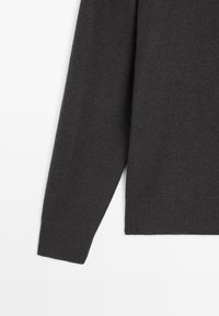 Ciemnoszary sweter dzianinowy z miękką teksturą, długimi rękawami i prążkowanym wykończeniem. Projekt jest prosty, bez widocznych wzorów czy akcentów.