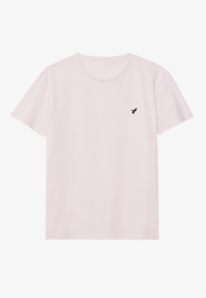 T-shirt rose clair à manches courtes et col rond avec un petit logo d'oiseau noir sur le côté gauche de la poitrine.