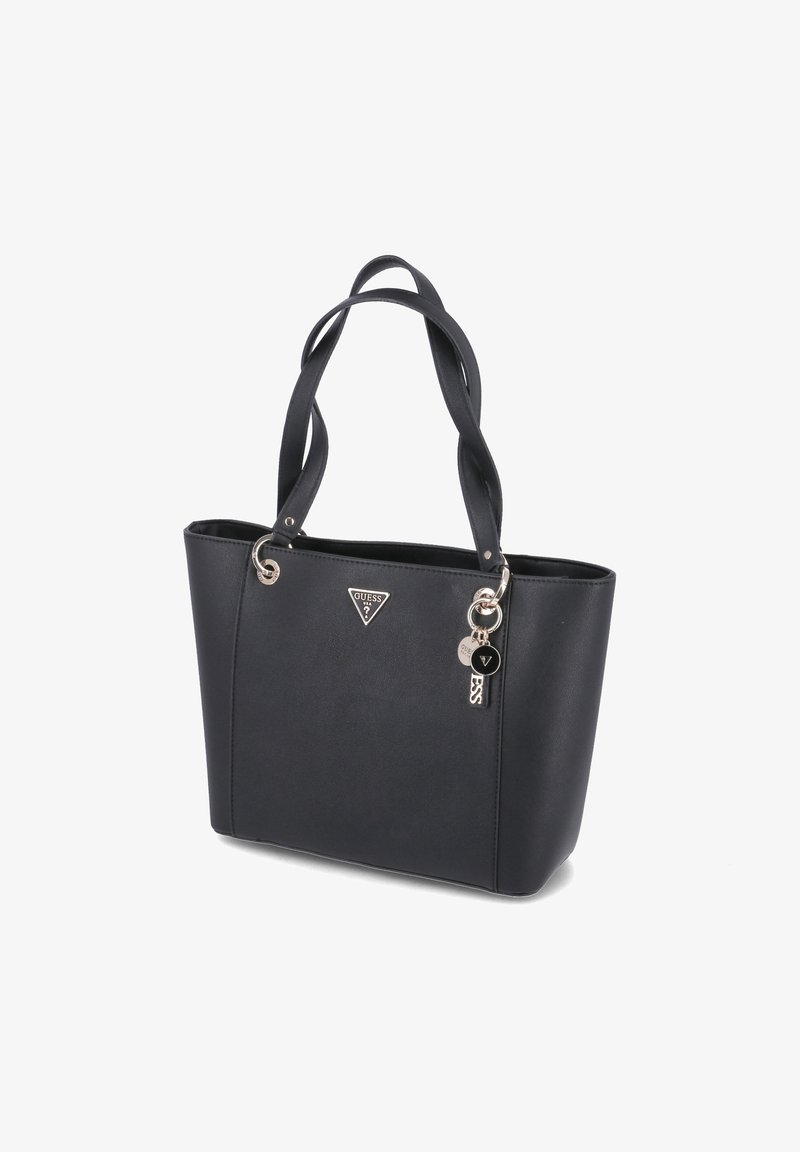 Borsa a tote nera in ecopelle con doppie maniglie, logo triangolare Guess e charm decorativi in metallo su sfondo bianco.