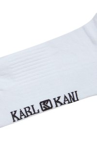 Hvide bomuldssokker med ribbet tekstur og sort "KARL KANI" logo øverst. Enkel design uden yderligere mønstre eller accenter.
