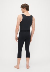 Black sleeveless tank top and leggings. Made from stretchy material with a fitted design. Leggings end below the calf. Branding on waistband.