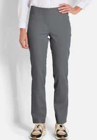 Grijze, aansluitende broek gemaakt van een gladde stof, met een platte voorkant en subtiele verticale strepen, gecombineerd met casual sneakers.