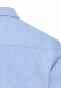 Light blue shirt with a smooth texture, soft fabric, and a standard collar. Features stitching along the shoulder and back seam.