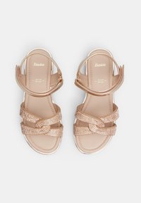Roosa kuldne sandaalid siledat viimistlust, risti minevate rihmade ja dekoratiivsete kristallidega. Kujundatud ankle strap'i ja pehmendusega tallaga.
