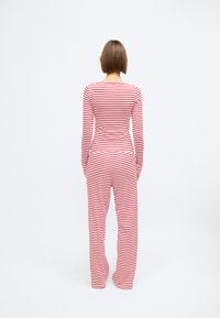 Σετ με μακρυμάνικη μπλούζα και παντελόνι σε κόκκινες και λευκές οριζόντιες ρίγες, κατασκευασμένο από μαλακό και ελαστικό ύφασμα. Φαρδιά παντελόνια με εφαρμοστή μπλούζα.