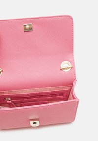 Rosa plånbok i syntetläder med strukturerad yta. Insidan har ett fack med dragkedja, kortplatser och detaljer i guldfärgad metall.