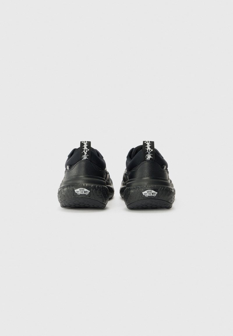 Sneaker nera con suola in gomma texturizzata, collare imbottito e linguetta del tallone bianca a contrasto con un motivo geometrico.