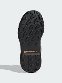 Semelle de chaussure en caoutchouc noir avec des motifs profonds pour l'adhérence, présentant un logo Continental central en orange. Surface texturée avec des motifs en relief.