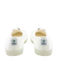 Fehér vászon slip-on cipők, texturált gumitalppal és zöld logó folttal. Minimalista dizájn és lekerekített orr jellemzi.