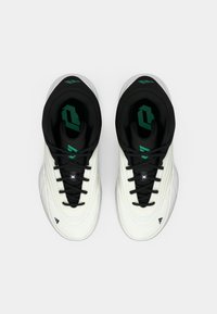 White athletic shoes with black accents, textured upper, and green logo on the tongue. Features laces and a cushioned collar for support.