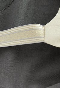 Grått tyg med en texturerad yta och ett krämfärgat accentband med guldstripes och en texturerad finish, vilket skapar en visuell kontrast.