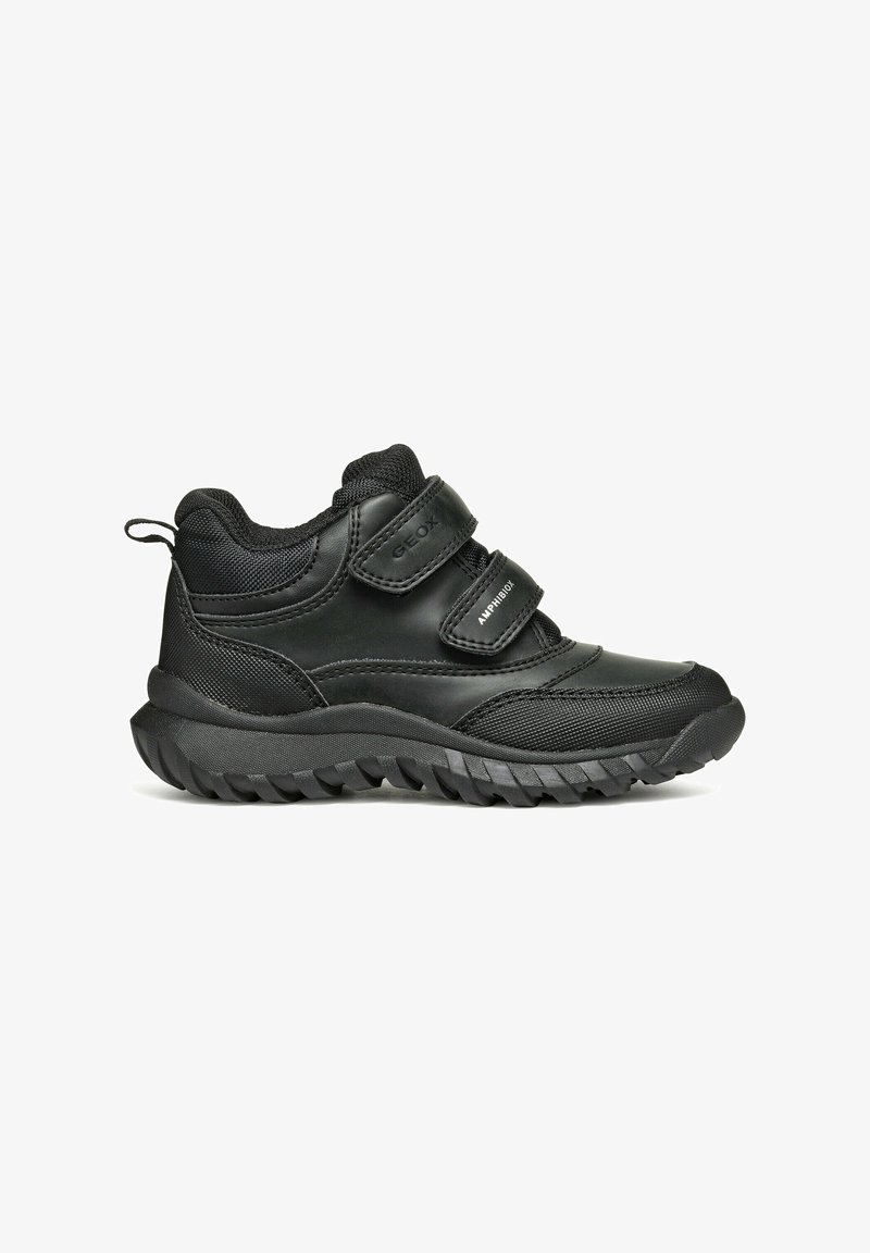 Zapatilla negra con material texturizado, dos correas de Velcro, collar acolchado y una suela de goma gruesa con un patrón de relieve.