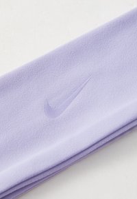 Purple Nike headband made of soft material, featuring a subtle embossed logo. The design is sleek with a smooth, textured finish.