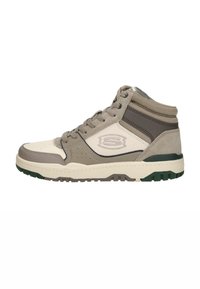 Mid-top sneaker featuring a beige and gray color scheme with a textured finish, perforated details, and a green rubber sole.