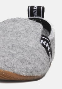 Grijze gevoerde slipper met een zwarte stoffen band met witte letters. Rondvormig, rubberen zooldetails en zachte textuur.