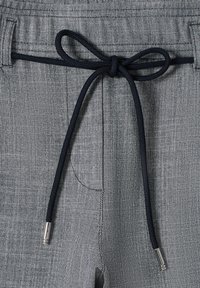 Shorts en tissu gris avec un cordon de serrage bleu marine orné d'embouts argentés, surface texturée et poches latérales.