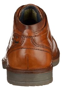 Bottes chelsea en cuir marron avec une finition lisse, bout rond et accents cousus. Elles sont dotées d'une semelle en caoutchouc texturée et d'un col rembourré.