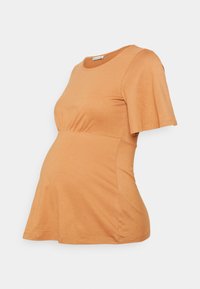 T-shirt de maternidade em laranja claro, feito de tecido suave. Apresenta mangas curtas e esvoaçantes, além de um design de cintura franzida. Decote redondo clássico.