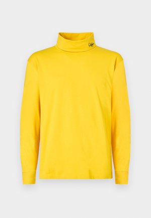 Heled kollane pika varrukaga turtleneck särk, millel on krae peal väike must tikandlogo, lihtne disain, esitleb valgel taustal.