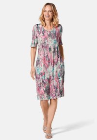 Knee-length jurk met bloemenpatroon in roze, teal en zwart. Korte mouwen, ronde halslijn en een gerimpelde taille. Gemaakt van lichtgewicht stof.