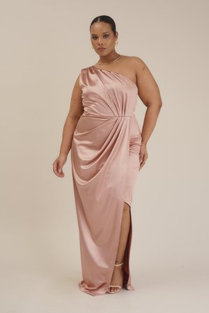 Abito in satin a spalla unica di colore rosa pallido, con tessuto drappeggiato, una profonda scollatura laterale e dettagli arricciati in vita. Modello con indosso sandali.