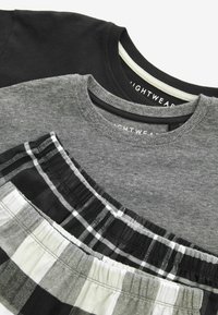 Drei Nachtwäsche-Oberteile in Schwarz, Grau und einem schwarz-weißen karierten Muster. Sie verfügen über runde Ausschnitte und unterschiedliche Texturen.