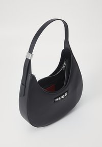 Black faux leather shoulder bag with a curved shape, silver-tone hardware, zippered compartment, and embossed logo detail.