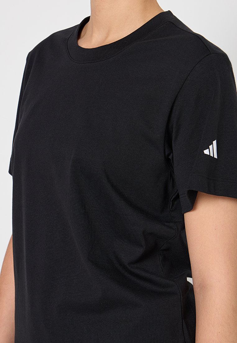 Maglietta sportiva nera a maniche corte indossata da una persona, con un piccolo logo Adidas bianco sulla manica sinistra.