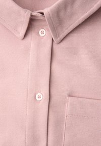 Polo shirt in morbido tessuto rosa con trama testurizzata, dotato di pattina con bottoni, colletto e taschino sul lato sinistro.