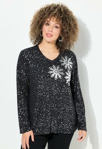 Maglietta nera a maniche lunghe con scollo a V, caratterizzata da motivi di schizzi bianchi e accenti di fiocchi di neve argento sul davanti. Texture morbida.