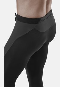 Zwarte sportleggings met een gestructureerd ontwerp, voorzien van een hoge tailleband en een discrete ritszak aan de achterkant.