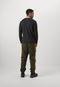 Under Armour ICON TRACK - Treniņtērpa apakšdaļas - expedition green