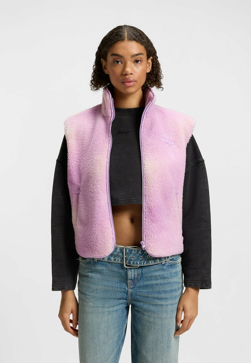 Fleece vest in gradient pink with a high collar and zip closure. Features short sleeves and a soft, textured finish.