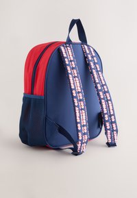 Red and navy fabric backpack with mesh side pocket, padded straps featuring "GO SPIDEY!" text, and a top carry handle.