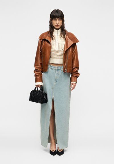 Καφέ δερμάτινο μπουφάν, κρεμ πλεκτό κοντό πουλόβερ, ανοιχτό μπλε τζιν φούστα με σκίσιμο, μαύρη τσάντα και μαύρες γόβες μυτερές.