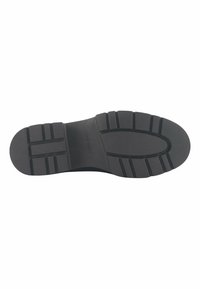 Black rubber shoe sole with tread pattern, featuring grooves for traction and a smooth central area. Stamped logo "NINE WEST."