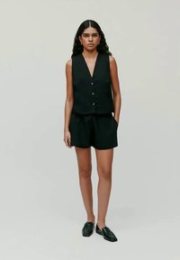 Black sleeveless vest with a V-neck and front button closure, paired with matching black shorts. Smooth fabric with a tailored fit.