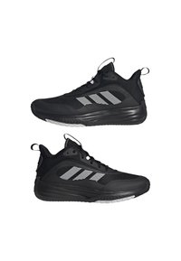 Chaussures de sport noires avec une tige en maille, une semelle en caoutchouc et trois rayures blanches sur le côté. Elles sont dotées d'un col rembourré et d'une languette pour un enfilage facile.