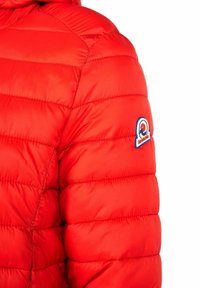 Rote Puffjacke mit gestepptem Muster. Mit Kapuze und einem blauen runden Logo auf dem linken Ärmel. Glatte, glänzende Oberfläche.