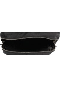 Sac en toile noir avec un extérieur lisse, présentant une large ouverture zippée et un intérieur sombre et spacieux.