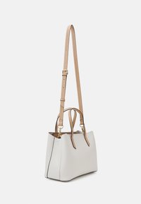 Piccola borsa bianca strutturata con manici corti e una lunga tracolla regolabile color beige, hardware dorato e dettagli neri lungo i bordi.