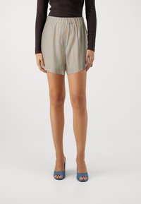 Lightweight, high-waisted shorts with light blue and beige vertical stripes, featuring an elastic waistband and a loose fit. Paired with blue heels.