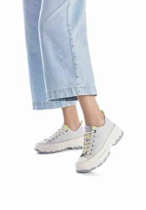 Zapatillas de deporte de encaje en gris claro con tejido texturizado, suela gruesa blanca y gris, y detalles en verde lima en la lengüeta y el talón.