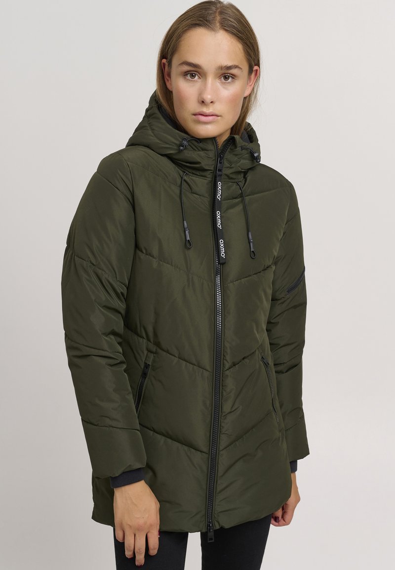 Padded green jacket with a zip front, adjustable hood, and black accents. Features angled seams and side pockets for utility.