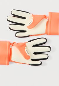Jasně oranžové rukavice s gumovými špičkami prstů, texturovanou tkaninou pro lepší úchop a upnutým zápěstím se zapínáním na zip.