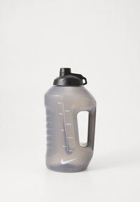Nike vandflaske i gennemskinnelig grå plastik med et sort skruelåg, ergonomisk håndtag og målemarkeringer langs siden.