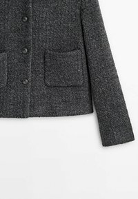 Veste en laine gris foncé texturée avec boutons sur le devant et deux poches plaquées carrées sur le bas devant, une manche visible.