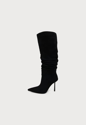 Botte noire en daim montant jusqu'au genou avec un bout pointu et un talon stiletto, avec un design supérieur décontracté.